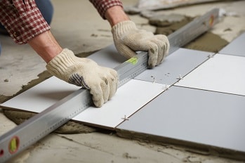 A flooring worker laying ceramic tile flooring in a home.