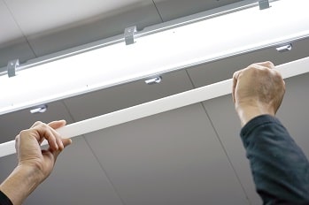 A general maintenance worker is replacing a bad light bulb.