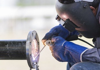 Pipefitter is welding and installing a flange on a pipe.