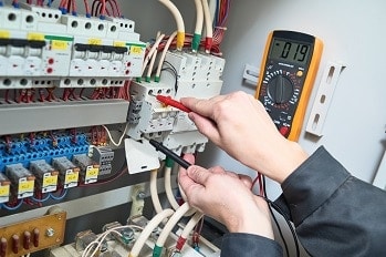 Industrial electrician troubleshooting electrical equipment in a factory